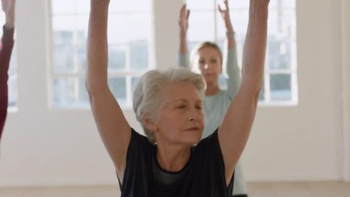 瑜伽课美丽的老年妇女锻炼健康的生活方式练习战士姿势享受工作室集体健身锻炼