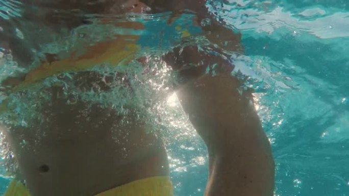 赤膊男子在游泳池游泳的水下视图，美丽的阳光照耀着水中的光线4k