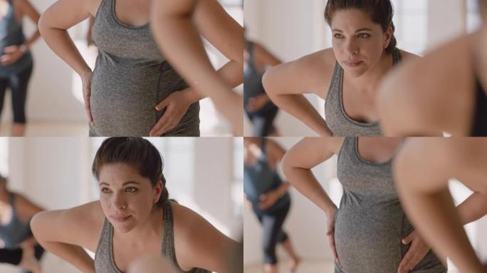 瑜伽课肖像年轻怀孕的西班牙妇女练习姿势抱着肚子享受健身工作室的集体锻炼