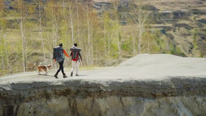 秋天，两名游客带着狗沿着岩石小径行走