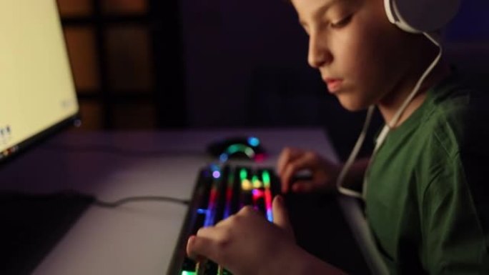 男孩晚上在霓虹灯室内用电脑玩网络游戏