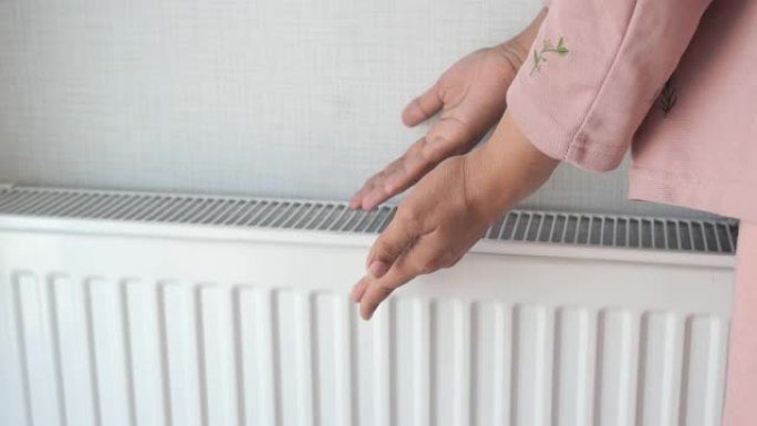 女人在家中电加热器附近暖手。