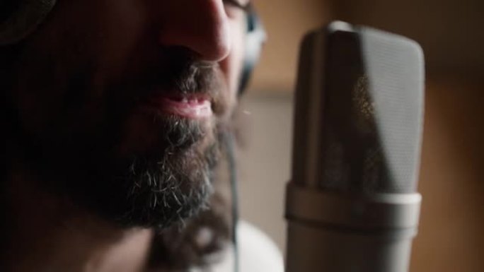 一个大胡子男人表演新歌的特写镜头，热情地对着麦克风唱歌，流口水出来了
