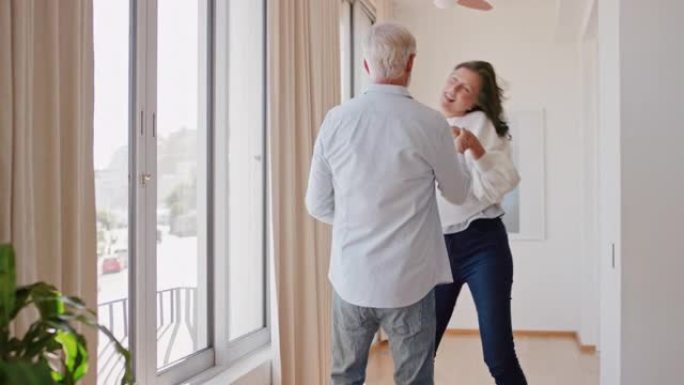快乐的成熟夫妇在家跳舞，享受成功的关系，享受庆祝周年退休的乐趣