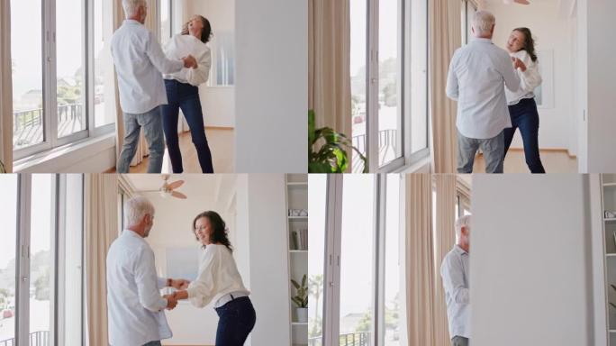 快乐的成熟夫妇在家跳舞，享受成功的关系，享受庆祝周年退休的乐趣
