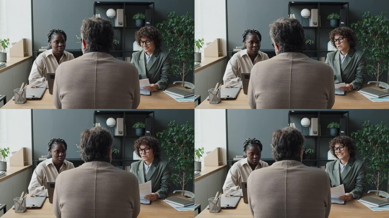 白人男子在办公室接受黑人和白人女性的工作面试