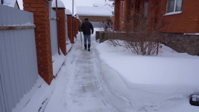 冬天，一个人在房子的院子里打扫雪。一名男子用铲子扫雪