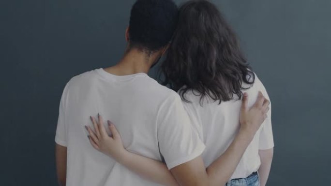 男人和女人站在一起，拥抱在灰色背景上表达爱与关怀的背景图