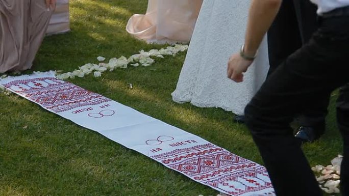 新娘和新郎踩在结婚毛巾上。