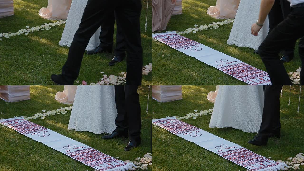 新娘和新郎踩在结婚毛巾上。