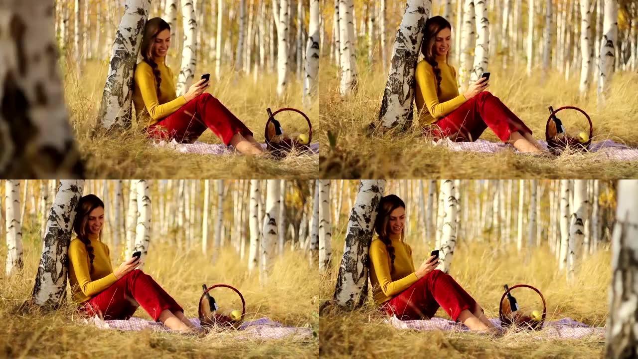 漂亮的年轻女子使用智能手机自然野餐