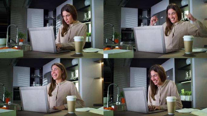 年轻成功的女商人在家厨房工作时在笔记本电脑上查看电子邮件的肖像。兴奋的女员工庆祝职业生涯中的成功交易