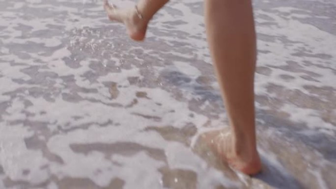 近距离女子脚赤脚走在海滩上享受海浪轻轻飞溅暑假女游客