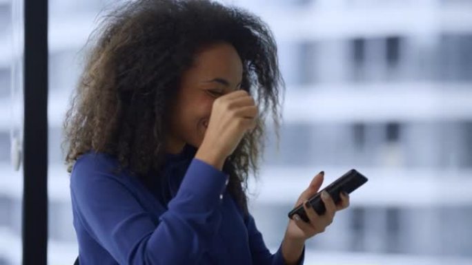 激动的非洲裔美国妇女在智能手机上庆祝好消息工作推广。