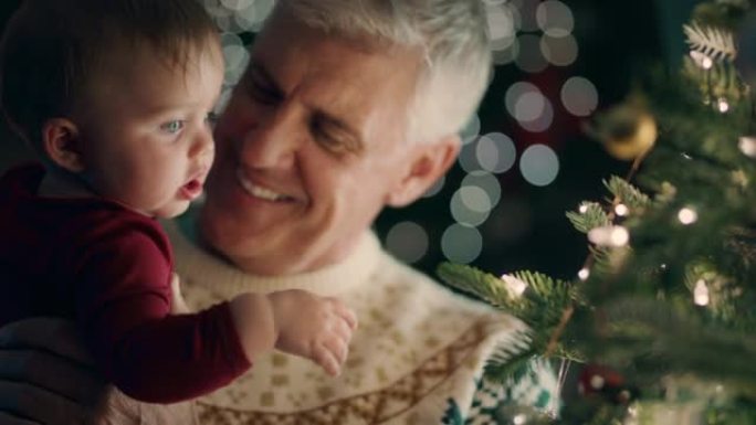 爷爷带着婴儿装饰圣诞树，用漂亮的装饰品和小玩意学步的孩子帮助爷爷在平静的夜晚在家中悬挂节日装饰品4k