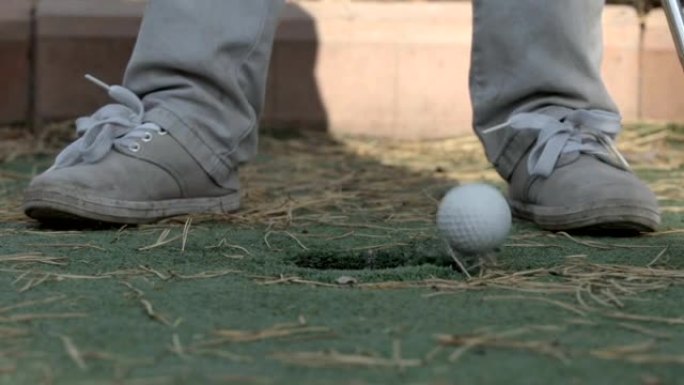 慢动作: 小球员的腿和高尔夫球跑到洞里
