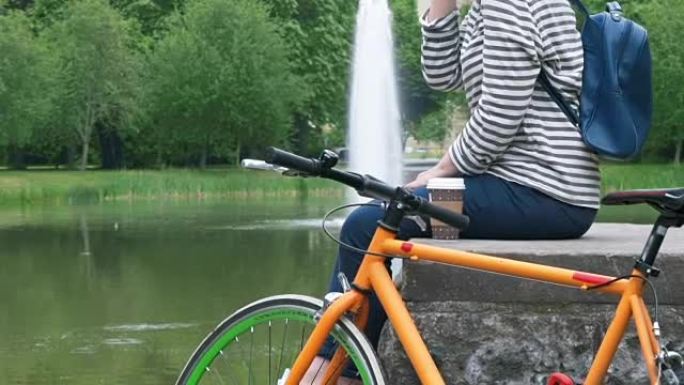 一个骑自行车的女人在公园里休息，用智能手机聊天