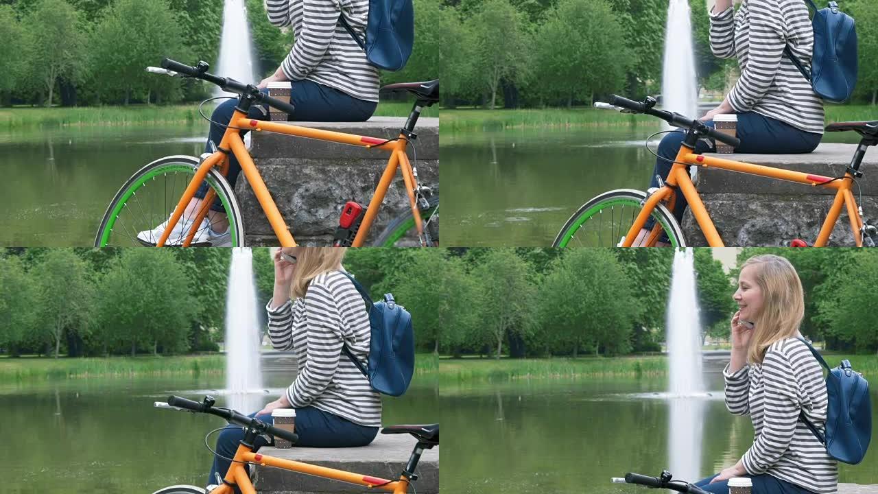 一个骑自行车的女人在公园里休息，用智能手机聊天