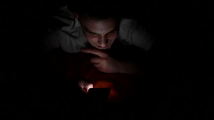 一个迷人的年轻人在床上使用智能手机的高角度视图