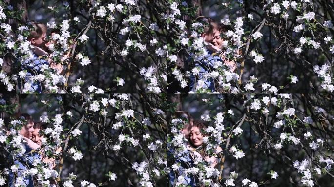 性感的夫妇在盛满小白花的树下开花的樱桃园中发现了隐私。英俊的年轻人拥抱漂亮的女孩