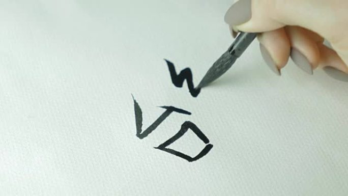 写中国象形文字的女人的手。女手握毛笔书法汉字，特写
