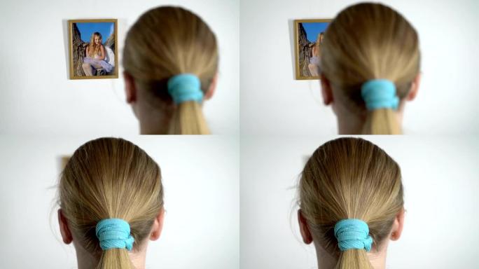 年轻女孩看着墙上相框里一个小女孩的照片