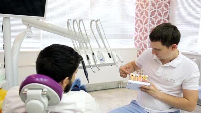 使用牙齿模型的年轻男性牙医说，患者正在讨论治疗方法