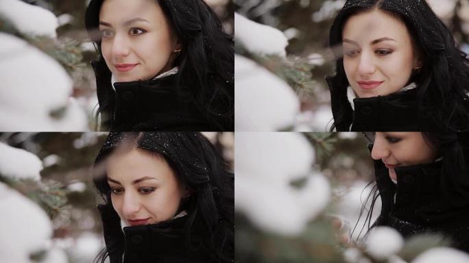 美丽的年轻女孩触摸云杉树枝上的雪
