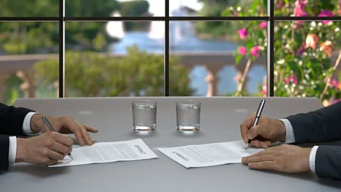 男人在餐桌上签署文件。