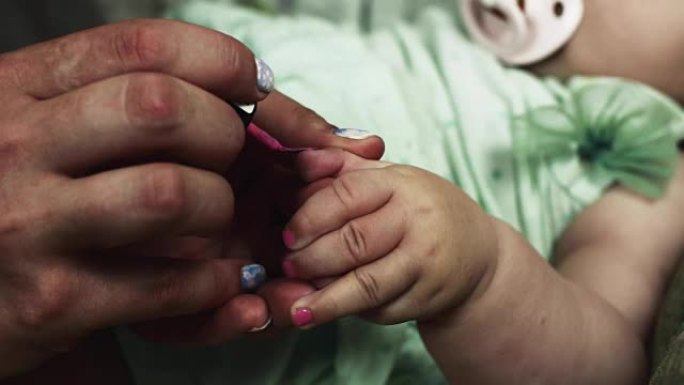 母亲用粉红色的漆覆盖女婴的指甲。家庭。做母亲。美