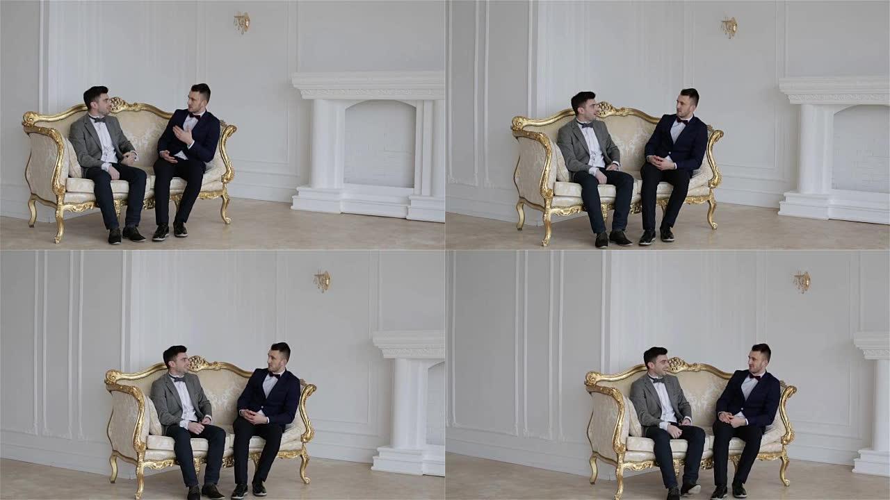 两个年轻英俊的男人坐在老式沙发上。