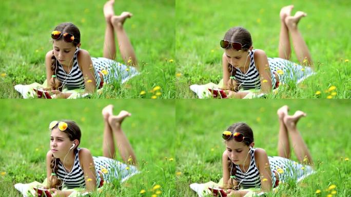 漂亮女孩躺在绿草地上，使用红色智能手机