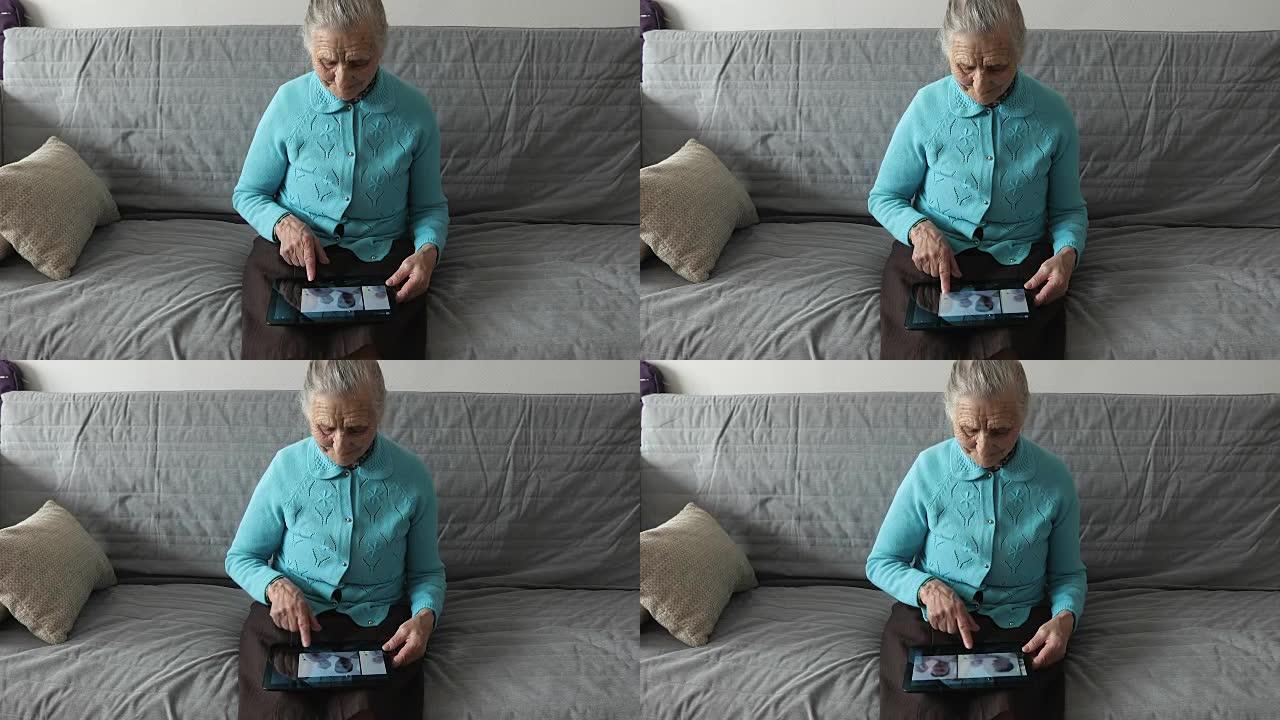 一位老妇人坐在沙发上，使用数字平板电脑。