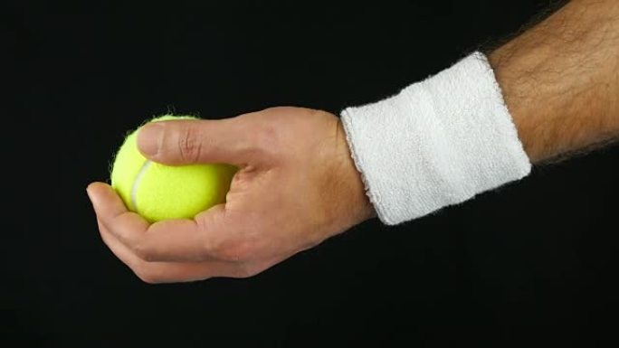 特写网球运动员的手，准备在击球前扔网球，黑色背景
