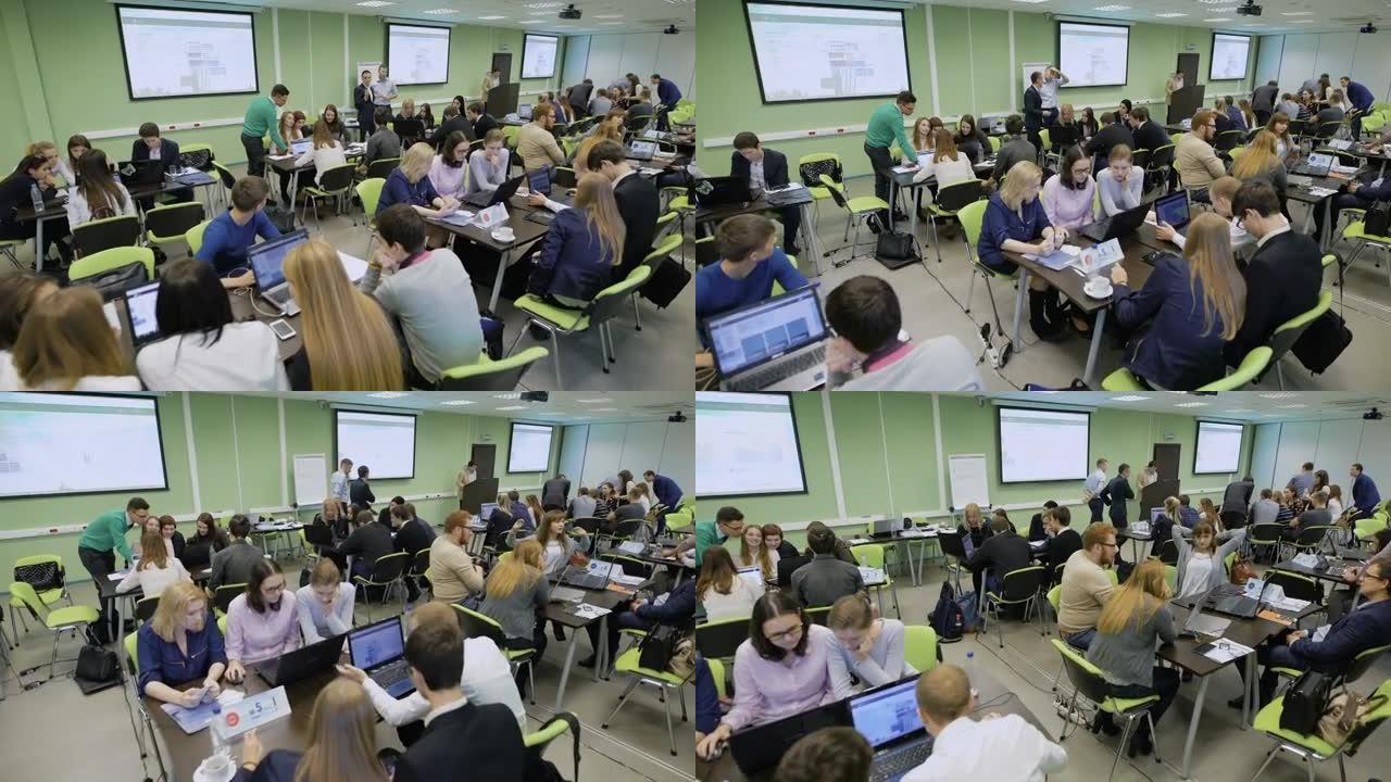 在大学课堂上与不同的学生团队进行教育竞赛。观众坐在桌子前，用笔记本电脑做练习和练习