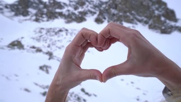 人类的手在雪山景观上塑造心形