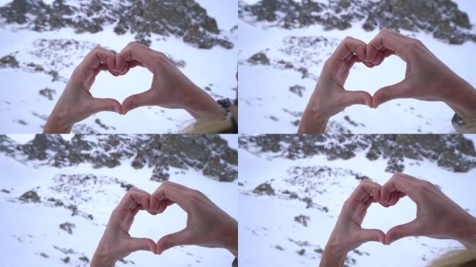 人类的手在雪山景观上塑造心形