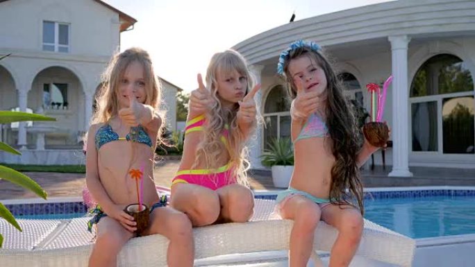 生活被宠坏的孩子，游泳池附近的有钱孩子摆姿势拍照，暑假的儿童名人，喝鸡尾酒的儿童派对