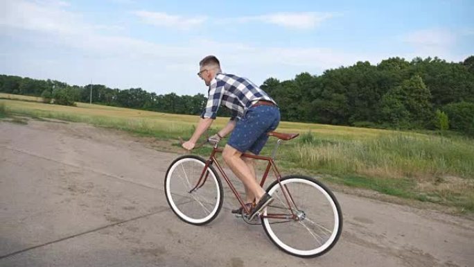 年轻英俊的男人骑着乡村公路上的老式自行车。运动的家伙在赛道上骑自行车。男性骑自行车的人在高速公路上骑