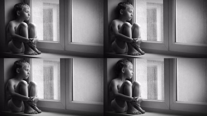 一个悲伤的男孩在倾盆大雨时坐在窗台上，无法离开公寓的黑白镜头。