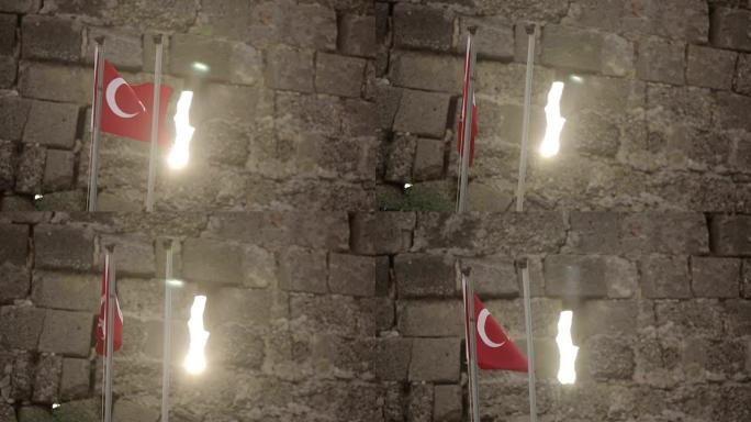 日落时在石墙背景上的土耳其国旗