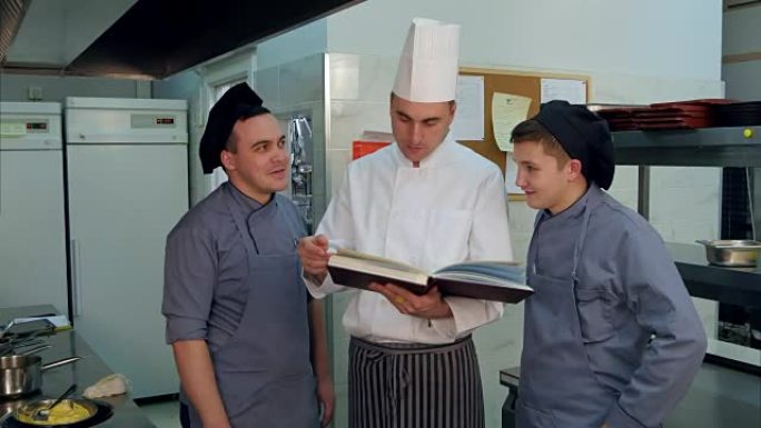 年轻的厨师学员与拿着食谱的厨师进行了积极的讨论