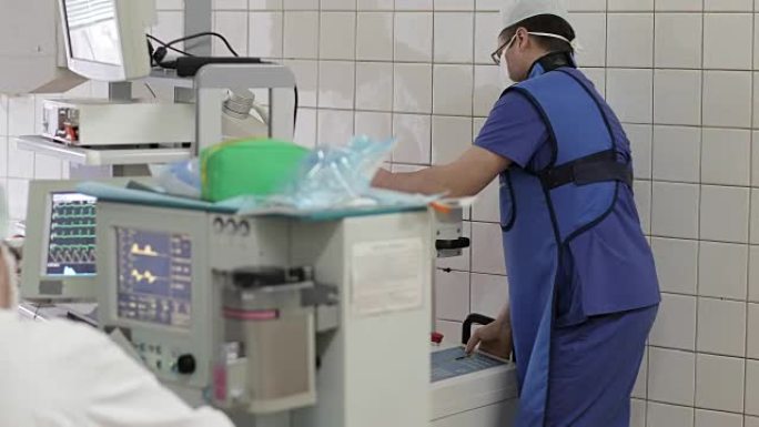 4k一名身穿制服的年轻医生在手术室移动医用x光设备。