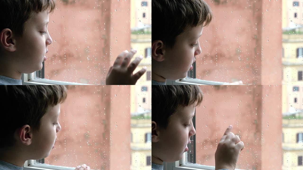 悲伤的孩子在雨中独自站在窗前