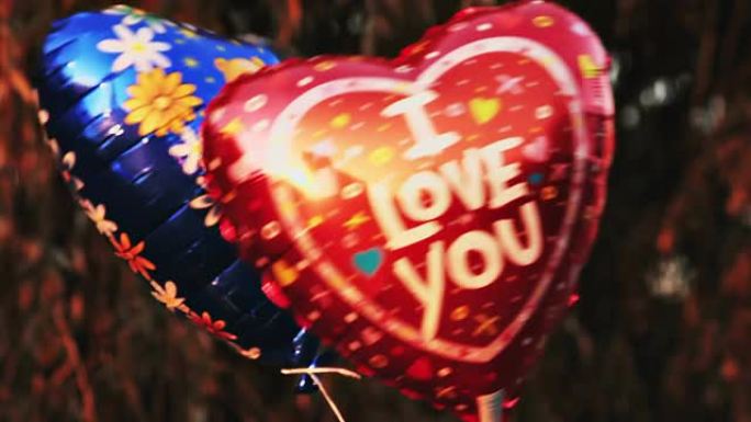 带有标题 “我爱你” 和泰迪熊图片的心形气球在风中摇曳