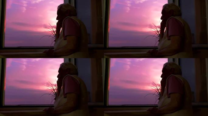 沉思-悲伤的老妇人在日落时看着窗外