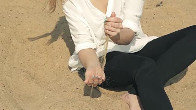 女孩坐在沙滩上，将沙子倒入
