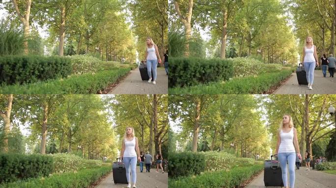 女孩带着一个手提箱沿着公园散步。