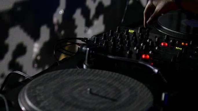 DJ和他的混音器的特写镜头，他正在一个拥挤的俱乐部里混合音乐