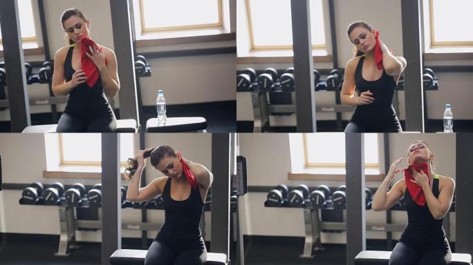 女人坐在健身房的长凳上进行体育锻炼后会擦汗